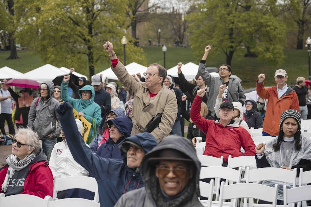 An outdoor crowd of people, some have their fists raised