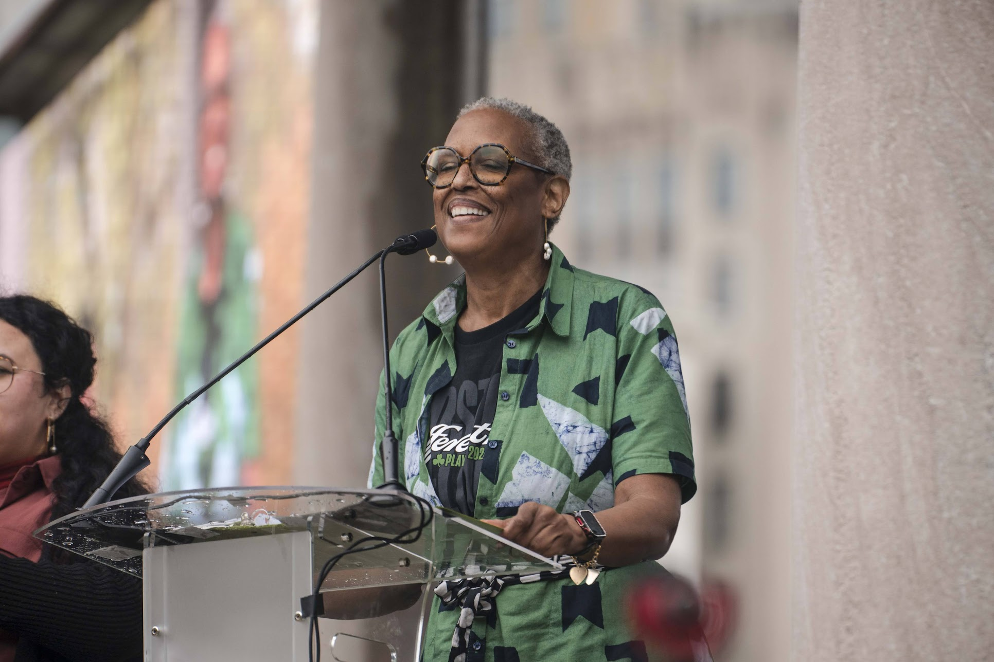 A person smiling and speaking into a microphone