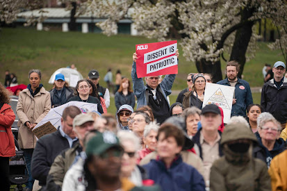 A group of people outside, some are holding signs