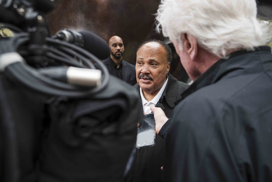 A man with a mustache speaking with reporters
