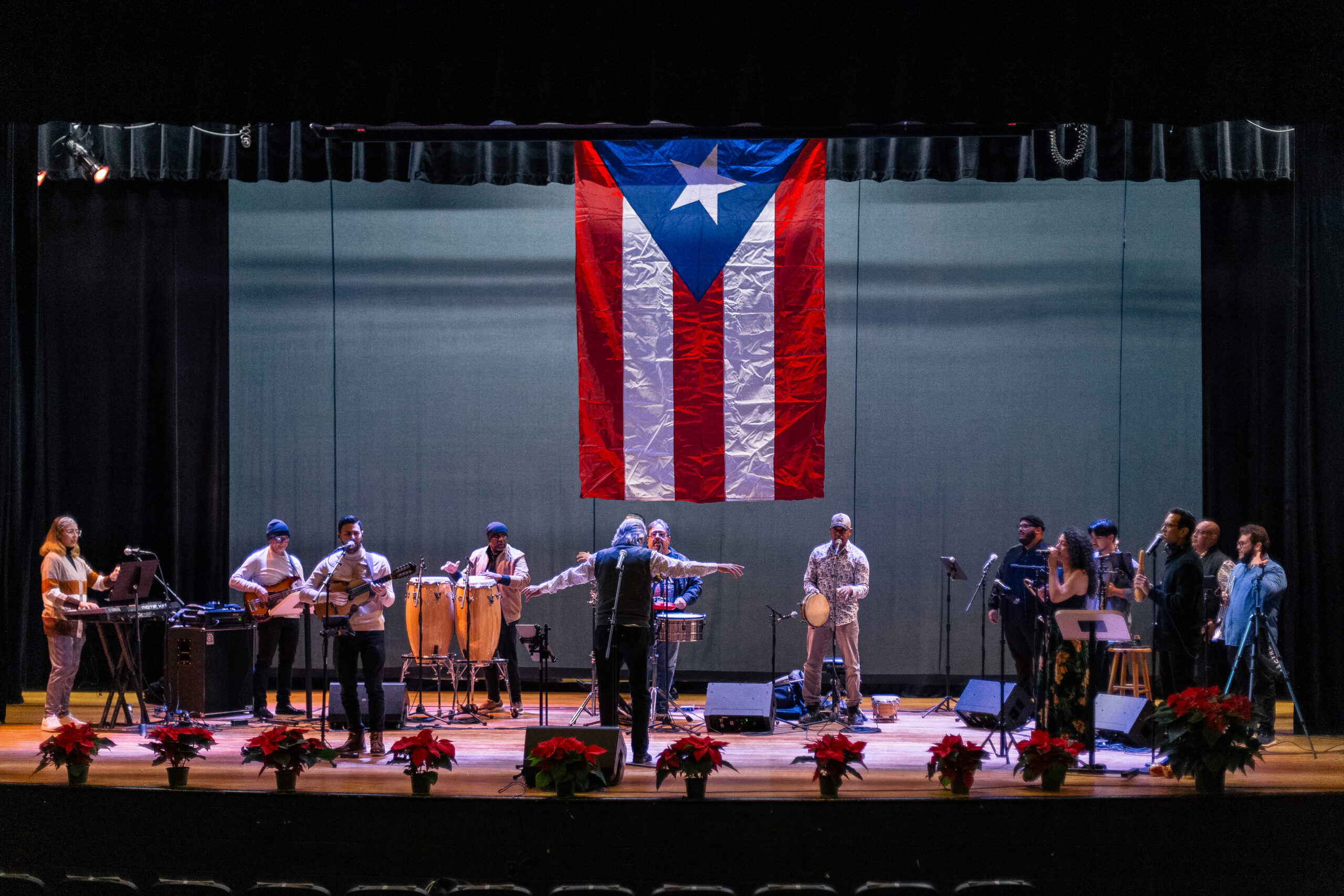 A group of musicians on stage with a Puerto Rican flag hanging above them.
